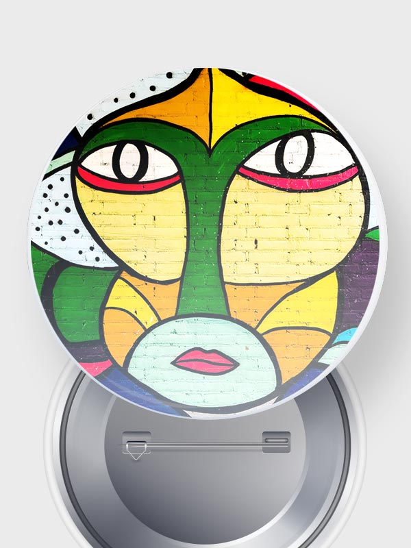 Un colorido rostro abstracto pintado sobre una superficie redonda, con atrevidas líneas negras, grandes ojos y labios rojos. El diseño utiliza verde, amarillo y varios colores brillantes para lograr un efecto impactante.