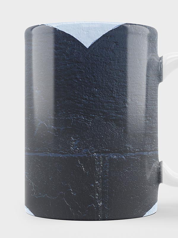 Taza de cerámica con una textura oscura que recuerda a la pizarra o la piedra. El diseño presenta una gran V invertida oscura cerca de la parte superior, realzada con bordes azul claro. El asa de la taza es blanca.