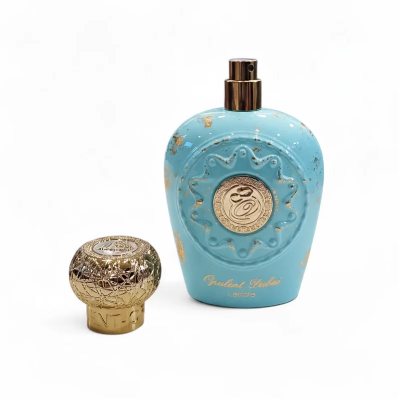 Frasco de perfume turquesa con detalles dorados y un decorativo tapón redondo dorado al lado. El frasco presenta detalles ornamentales y escritura árabe dorada, y lleva la etiqueta "Opulent Dubai Lattafa".