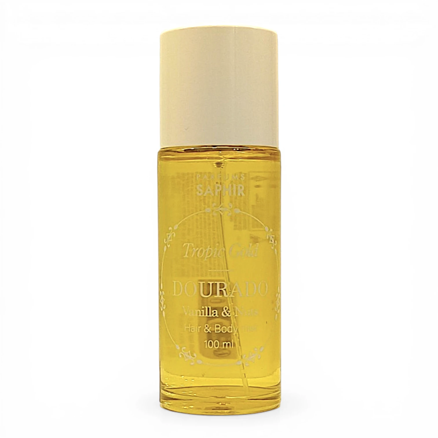 Frasco transparente de Perfums Saphir Dourado Tropic Gold Vanilla & Musk Hair & Body oil, 100 ml, con tapón blanco y líquido amarillo en el interior, fotografiado sobre un fondo blanco liso.