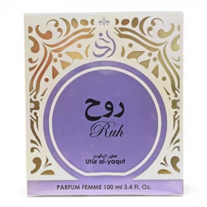 Caja de perfume con motivos ornamentales dorados, un gran círculo morado en el centro y texto en árabe sobre la palabra Ruh. En la caja también se lee Utūr al-yaqut, PARFUM FEMME, y 100 ml 3.4 Fl. Oz.