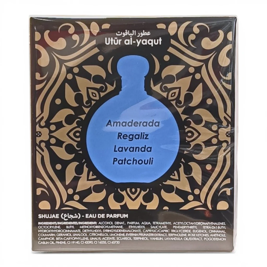 Una caja de perfume con la etiqueta Utúr al-yaqut presenta un diseño de frasco azul con las notas olfativas: Amaderada, Regaliz, Lavanda y Pachulí, sobre un fondo decorativo negro y dorado.