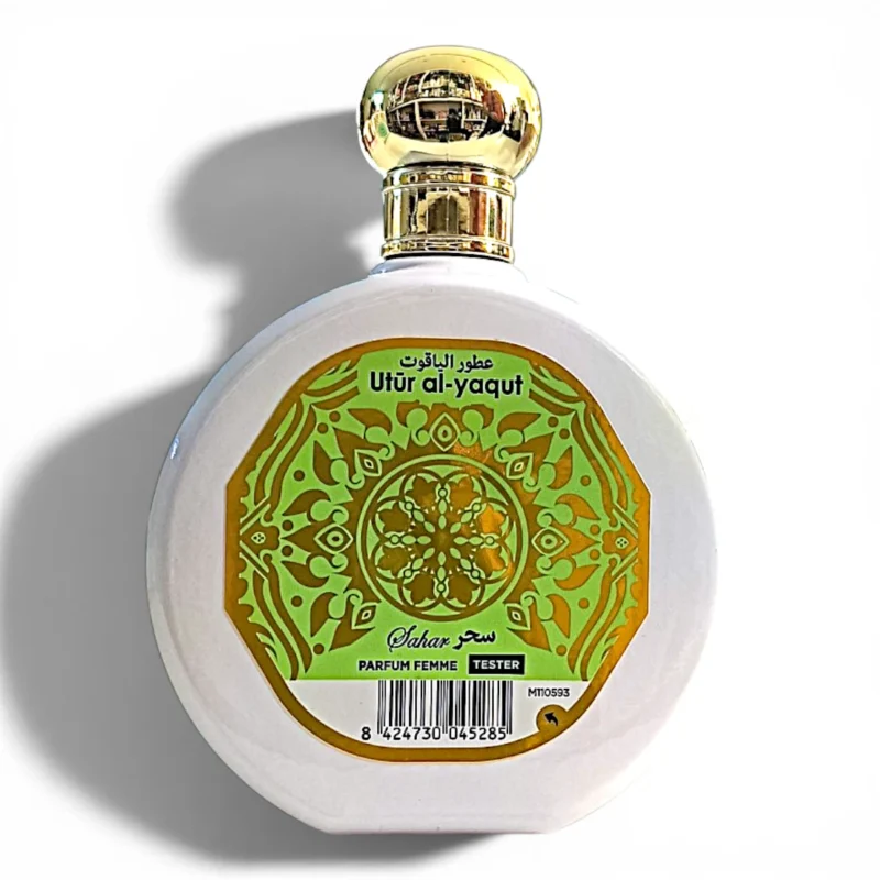 Frasco redondo de perfume blanco con tapón dorado. La etiqueta presenta diseños ornamentales verdes y dorados, texto en árabe e inglés en el que se lee Utūr al-yaqūt y Parfum Femme Tester. En la parte inferior aparece un código de barras. Frasco redondo de perfume blanco con tapón dorado. La etiqueta presenta diseños ornamentales verdes y dorados, texto en árabe e inglés en el que se lee Utūr al-yaqūt y Parfum Femme Tester. En la parte inferior aparece un código de barras.