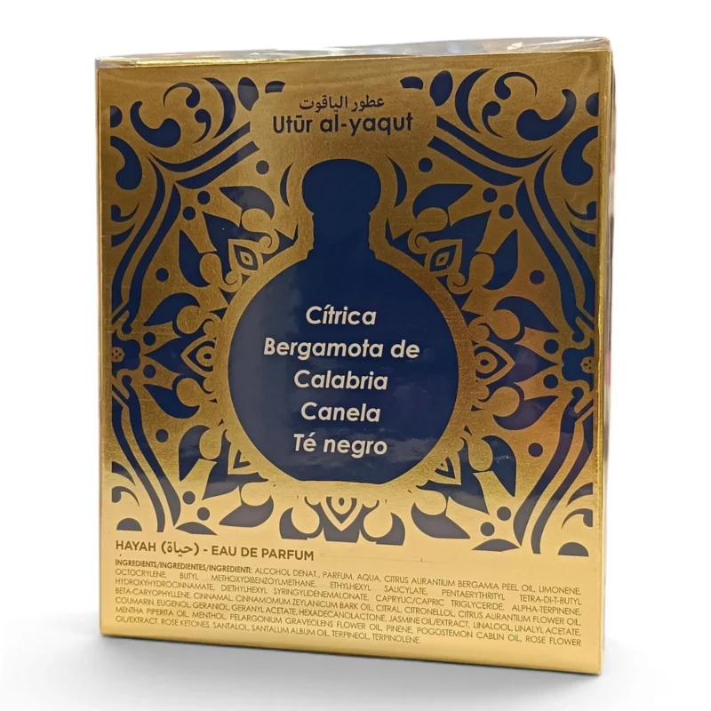 Caja de perfume dorada y azul con diseños ornamentados, texto en árabe y español y una lista de aromas: cítricos, bergamota de Calabria, canela y té negro. En la parte superior aparece la marca Utr al-yaqut. Caja de perfume dorada y azul con diseños ornamentados, texto en árabe y español y una lista de aromas: cítricos, bergamota de Calabria, canela y té negro. En la parte superior aparece la marca Utr al-yaqut.